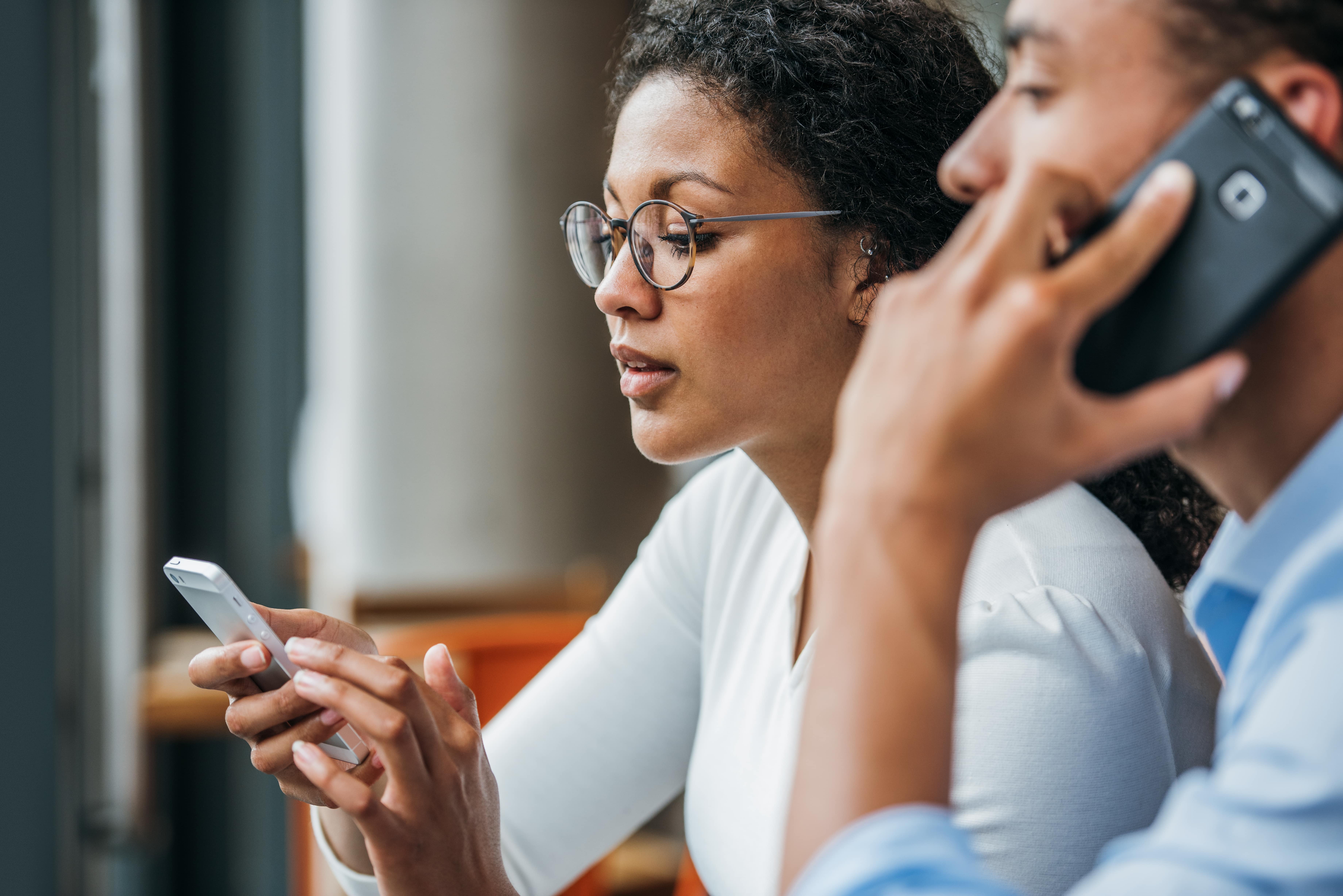 Photograph showing 2 people using their phone